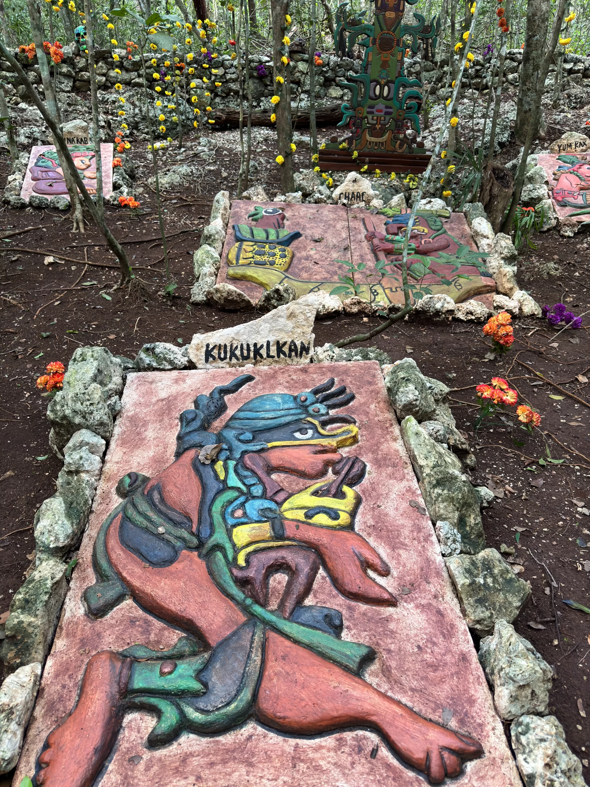 A Mayan-inspired graveyard with colorful carvings and decorations in the Cancun jungle.