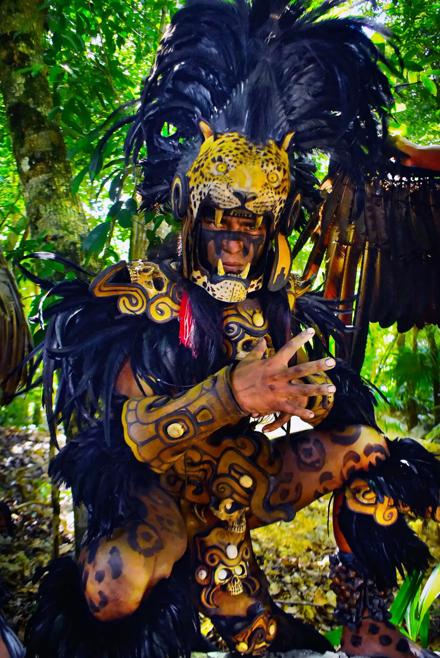 Performer dressed as a jaguar warrior in traditional costume with feathers and face paint during a cultural show in the jungle