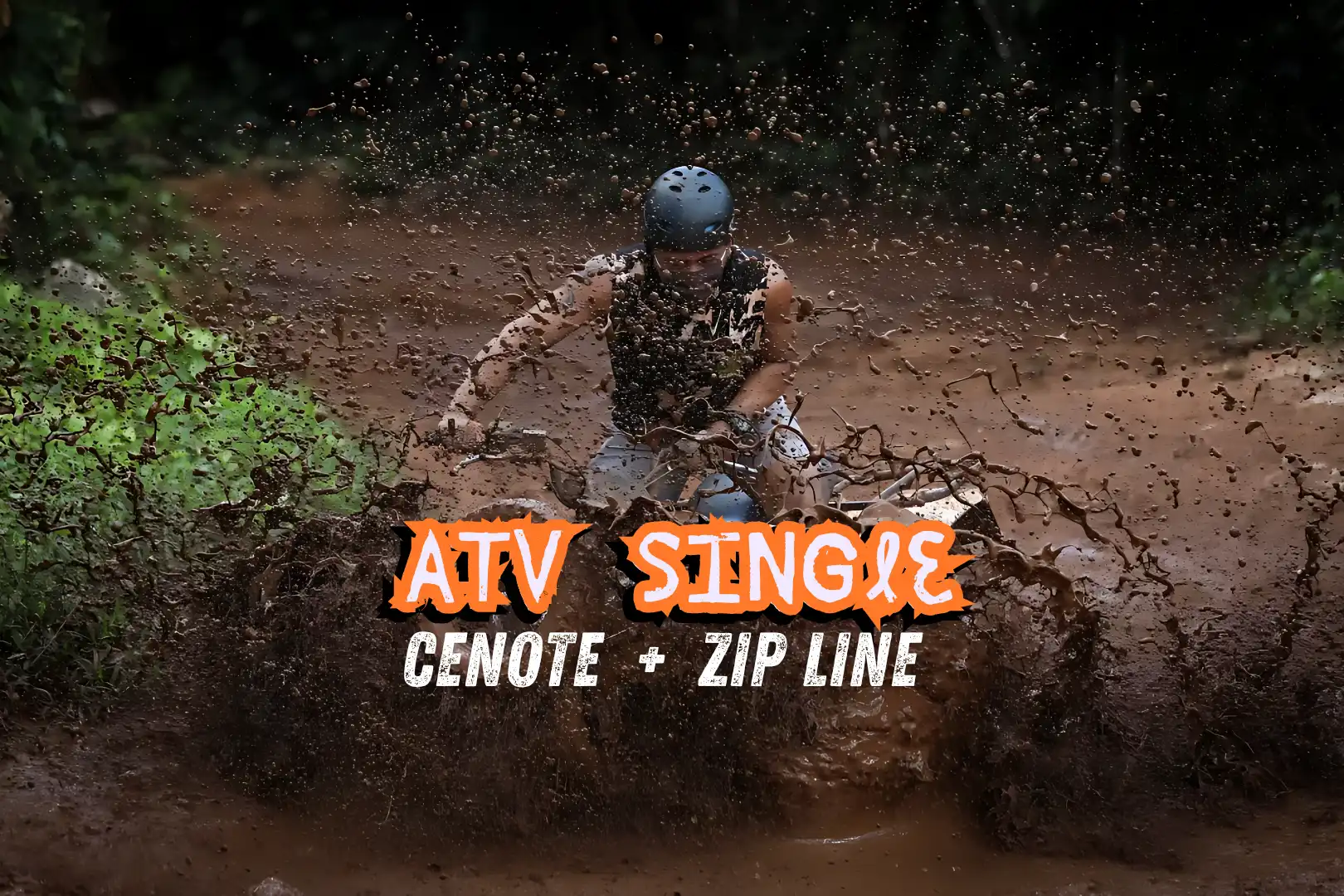 Man riding a single ATV through mud on a jungle trail, splashing water and dirt.