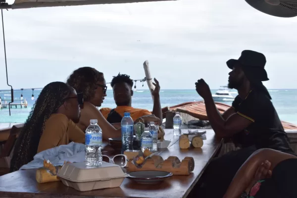 A group of friends enjoying a meal by the beach in Puerto Morelos, with a view of the ocean.