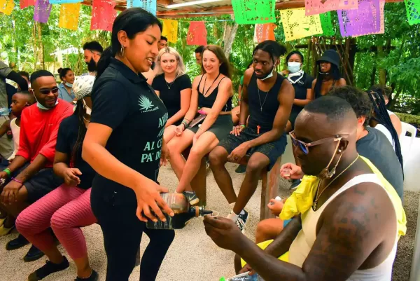 A group of people seated together during a tequila-tasting session in the Cancun jungle, as a staff member pours drinks.