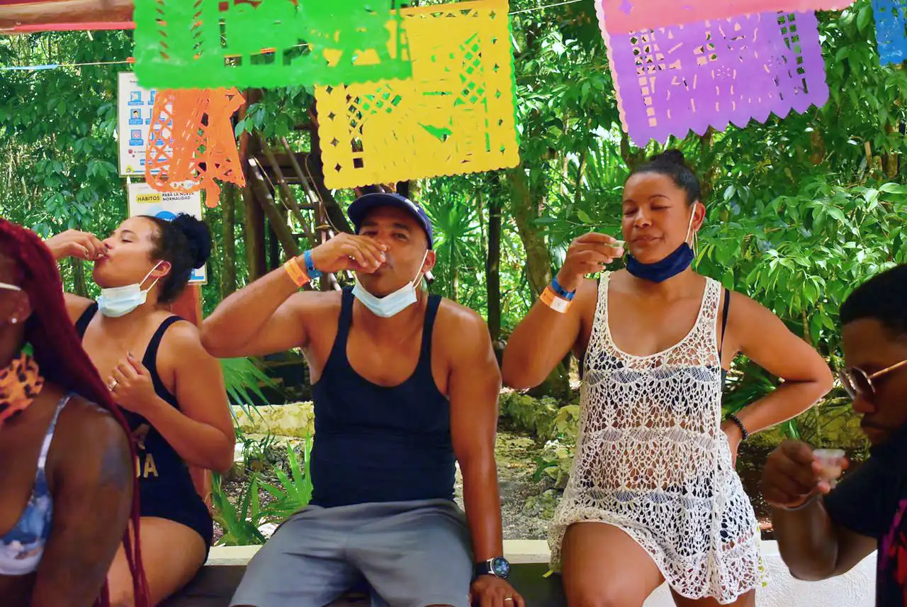 Group of people enjoying a tequila tasting experience under a shaded outdoor area.