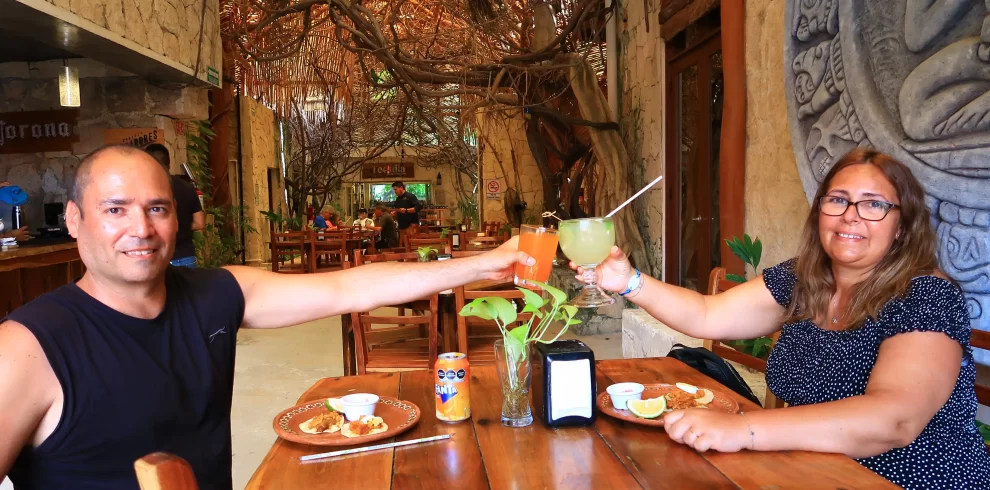 A couple toasting with cocktails in a cozy Cancun restaurant.