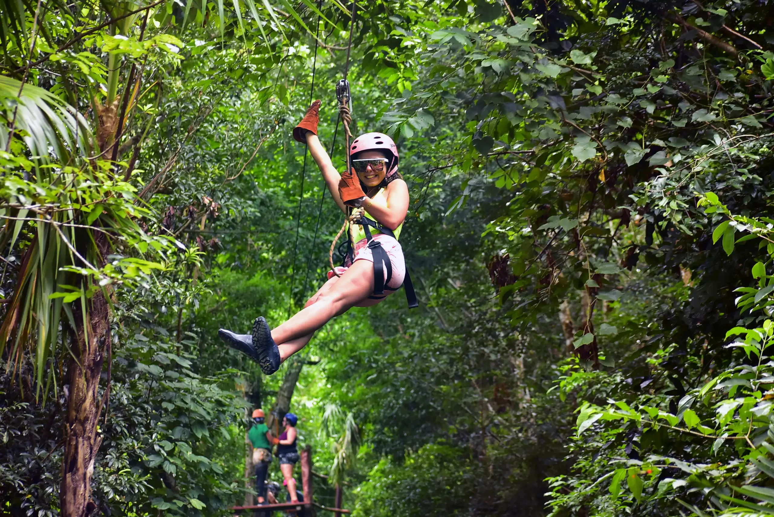 Woman ziplining through the forest canopy in Cancun.