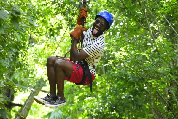 Man smiling and sticking his tongue out while ziplining.