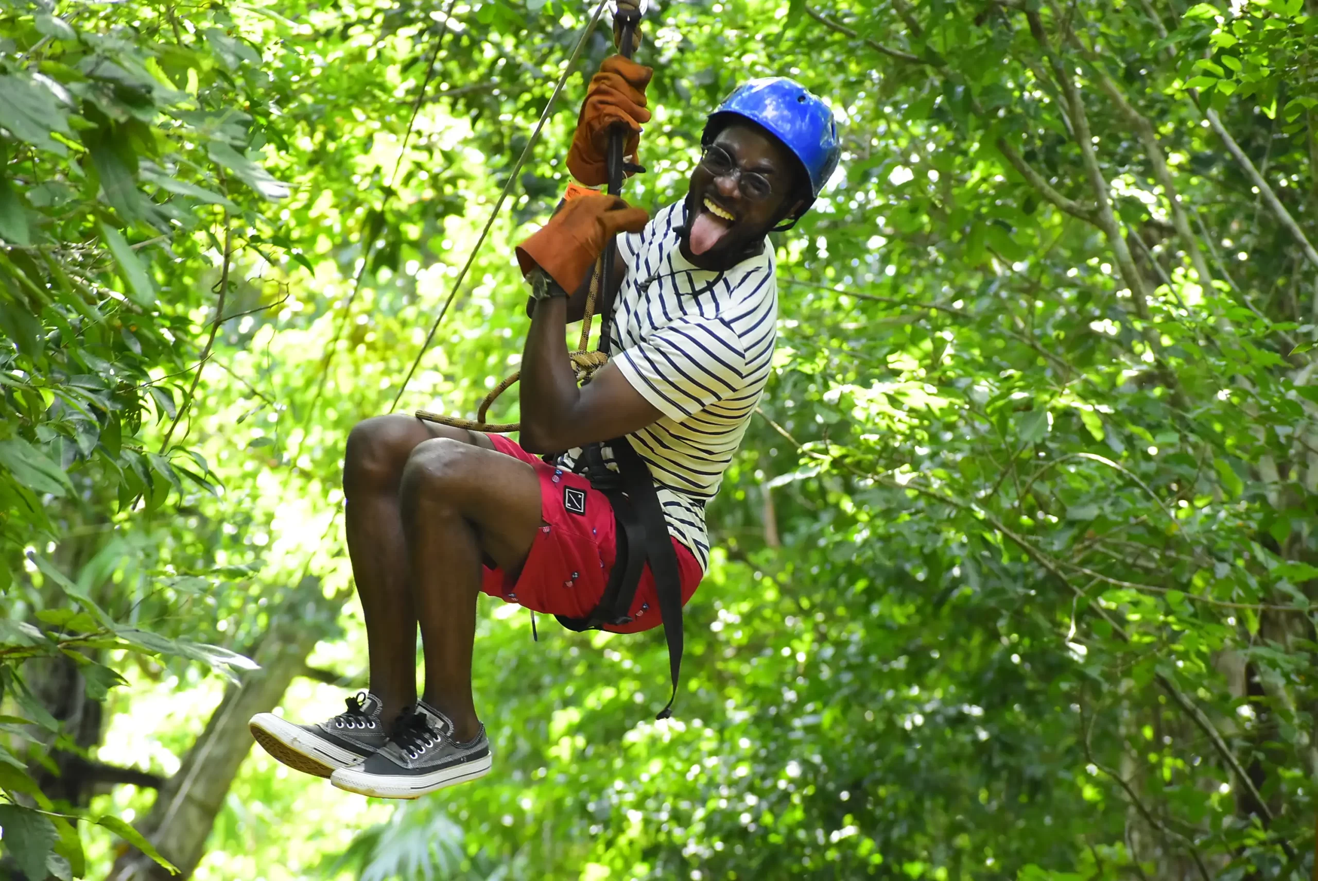 Man smiling and sticking his tongue out while ziplining.