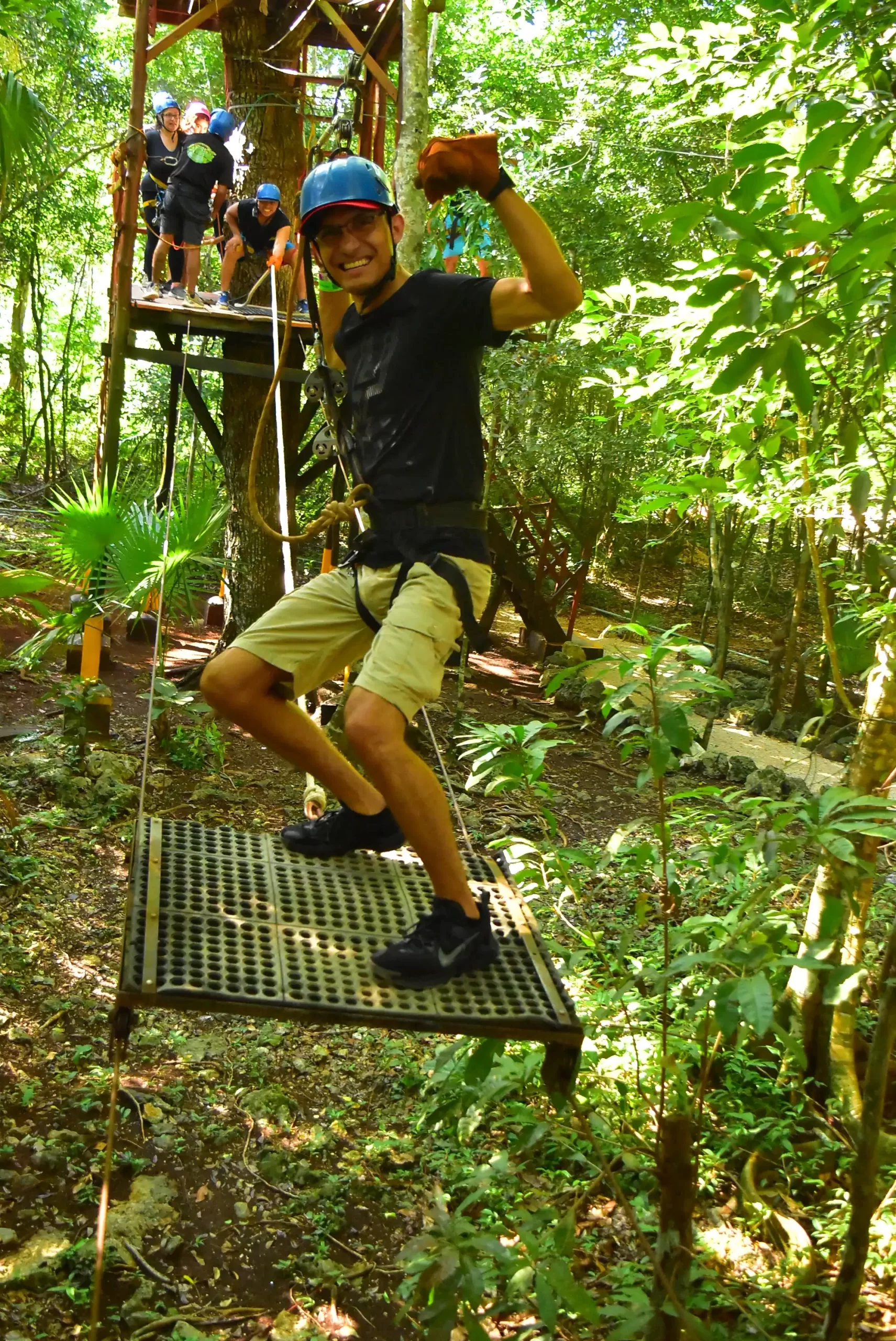 A man preparing to zip-line from a platform in the jungle, smiling as he gets ready for the adventure ahead.