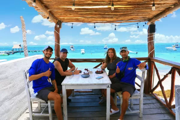 Group of friends dining at a beachside restaurant with a stunning view of the turquoise waters.