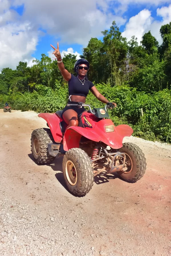 Woman riding an ATV and flashing a peace sign in Cancun.