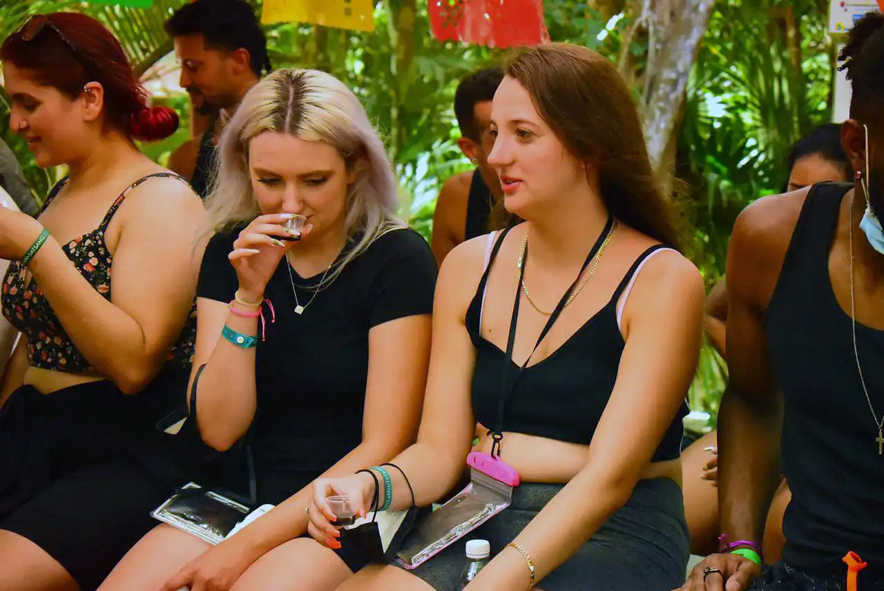 Two women sitting side by side, tasting tequila and enjoying a break from their outdoor adventure.